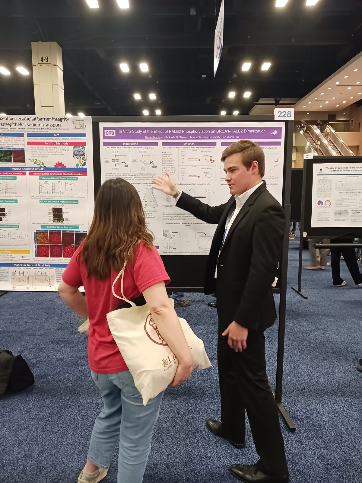 A student presenting a poster and answering a visitor&rsquo;s question