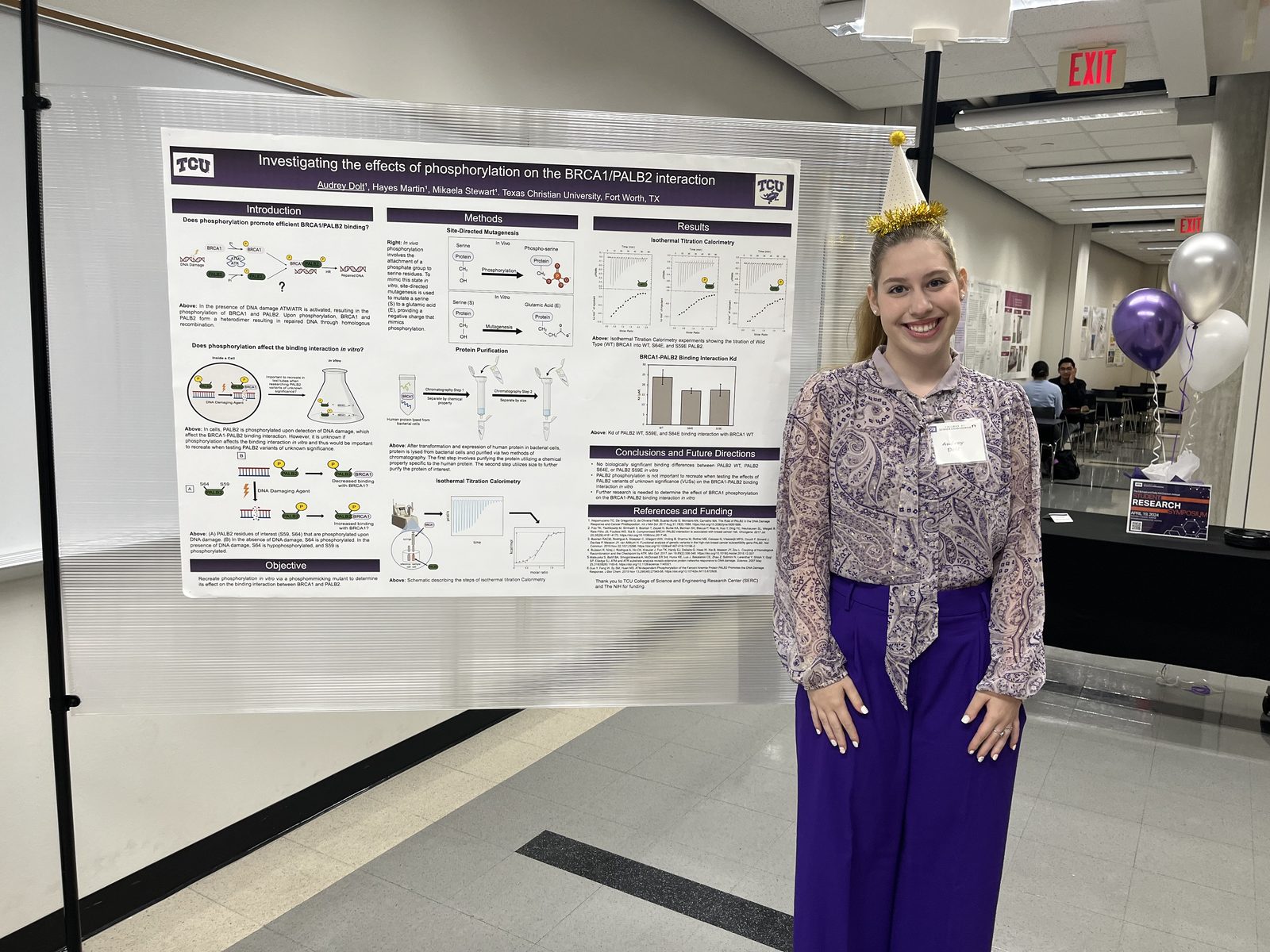 Audrey presenting a phosphorylation poster while wearing a party hat
