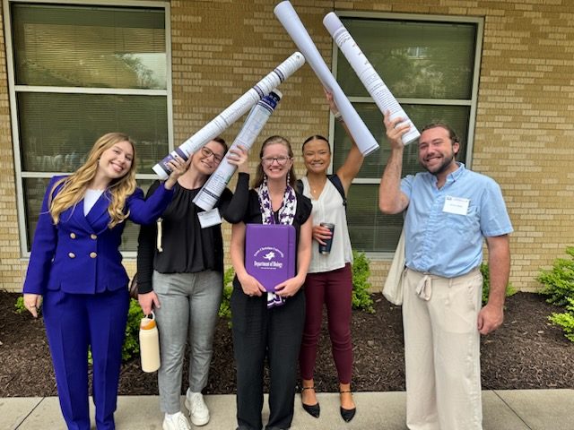 Lab members holding poster tubes overhead like a frame