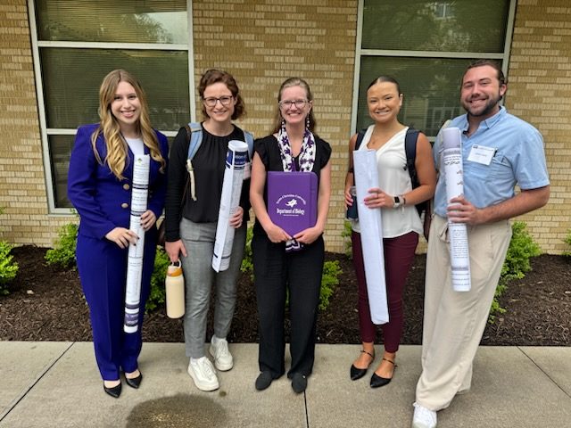 Five lab members posing with poster tubes outside